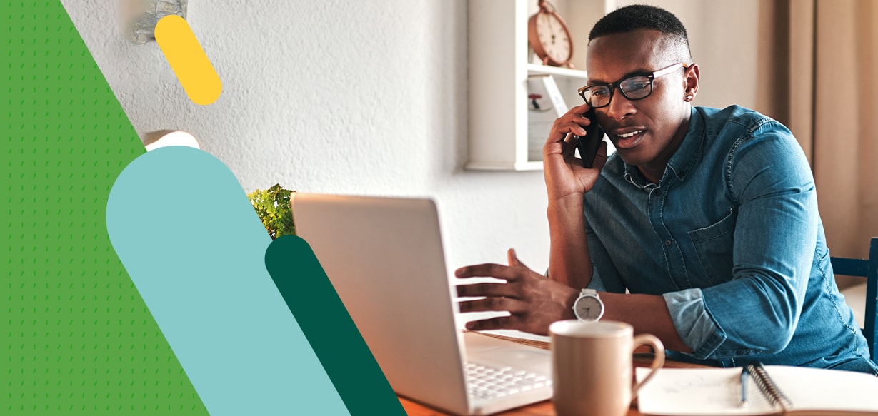 Man talking on phone while working on laptop