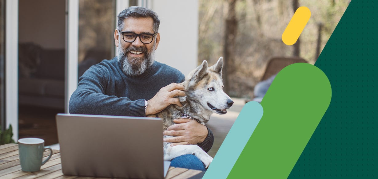 Man outside with dog watching laptop