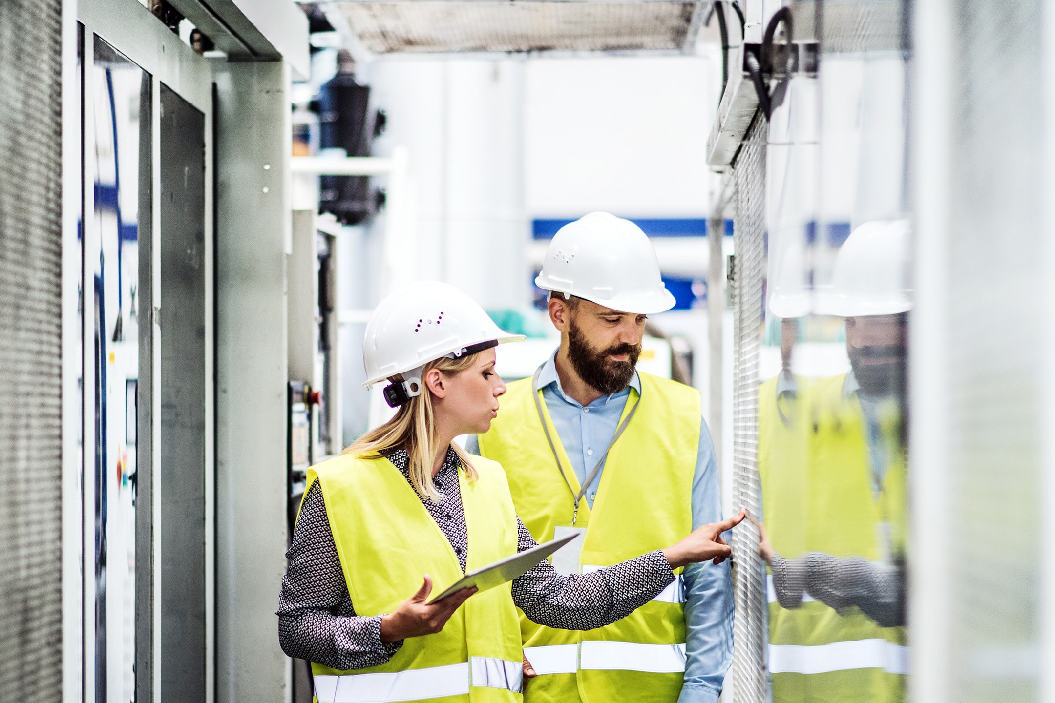 Two workers on factory floor in hard hats 