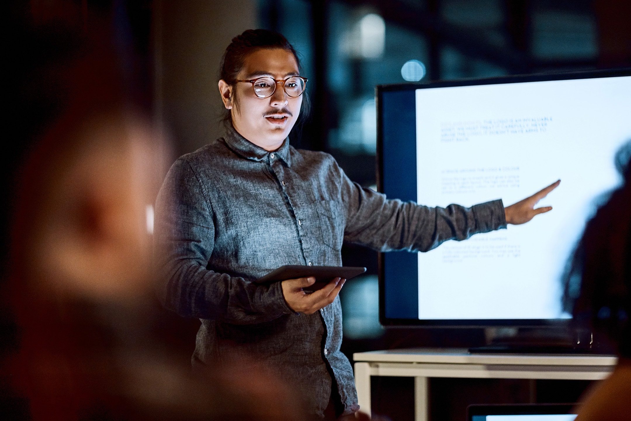 Man pointing to TV monitor holding iPad