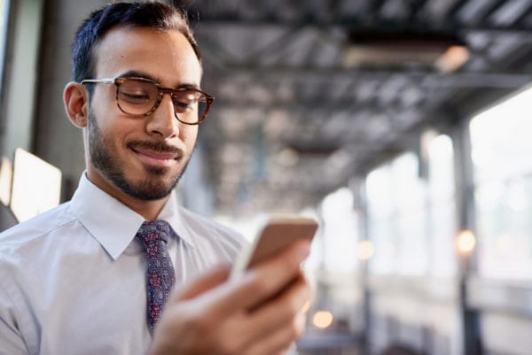 Man in tie and glasses looking at smart phone