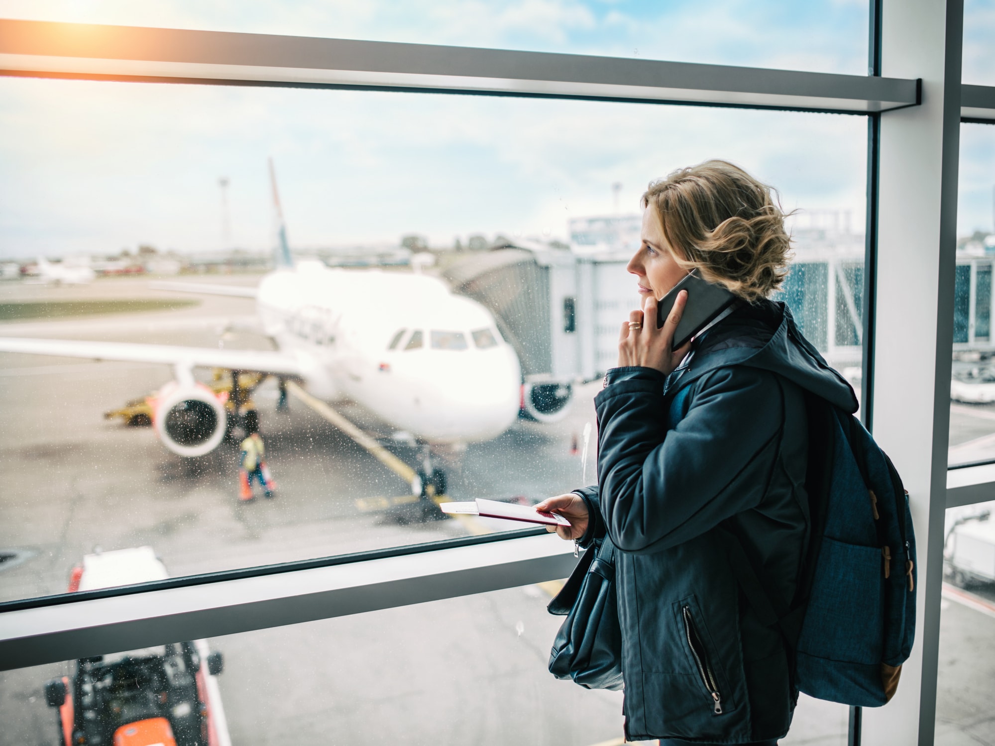 A woman in a green coat on wating for her plain at an airport