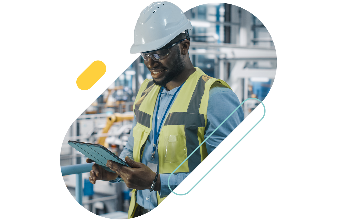 Man in a yellow safety vest working on a tablet computer in a warehouse